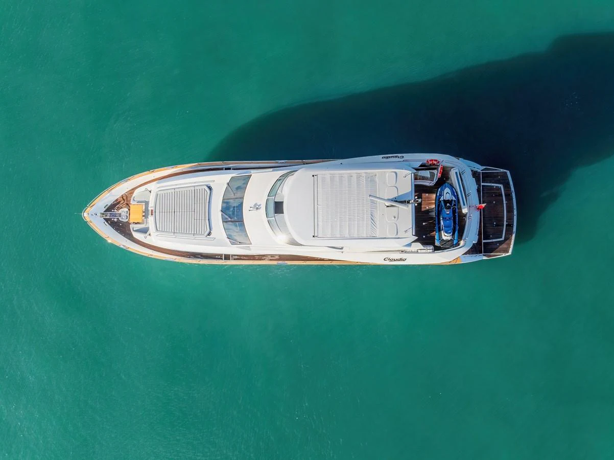 An aerial view of a sleek yacht cruising through clear turquoise waters. aboard CLOUDIA Yacht for Sale
