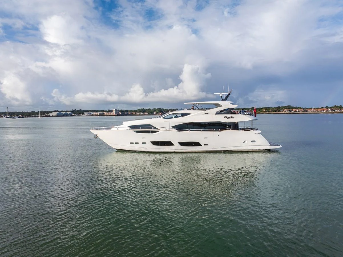 A sleek and modern yacht glides gracefully on calm waters under a partly cloudy sky. aboard CLOUDIA Yacht for Sale