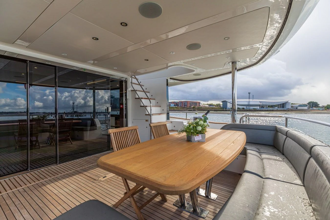 The aft deck features a spacious dining area with a wooden table and comfortable seating, perfect for alfresco meals with a view. aboard CLOUDIA Yacht for Sale