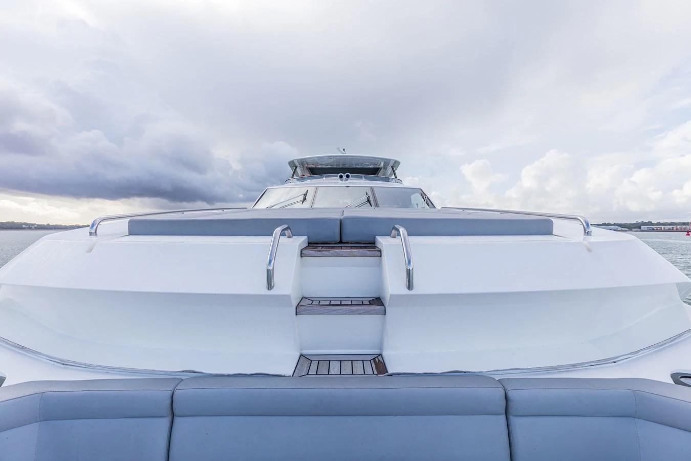 The yacht's sleek exterior design is showcased from a head-on perspective, highlighting its modern lines and spacious deck. aboard CLOUDIA Yacht for Sale