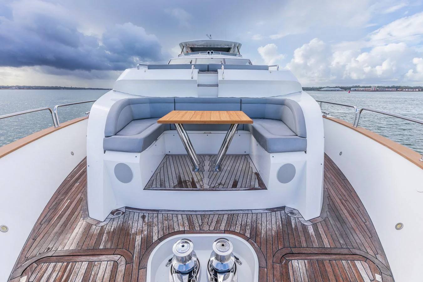 The aft deck features a stylish seating area with a wooden table, perfect for outdoor dining and relaxation. aboard CLOUDIA Yacht for Sale