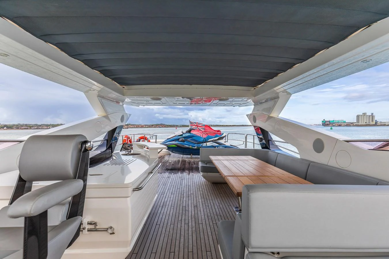 The aft deck features a comfortable seating area with a wooden table, offering a perfect spot to enjoy the view. aboard CLOUDIA Yacht for Sale