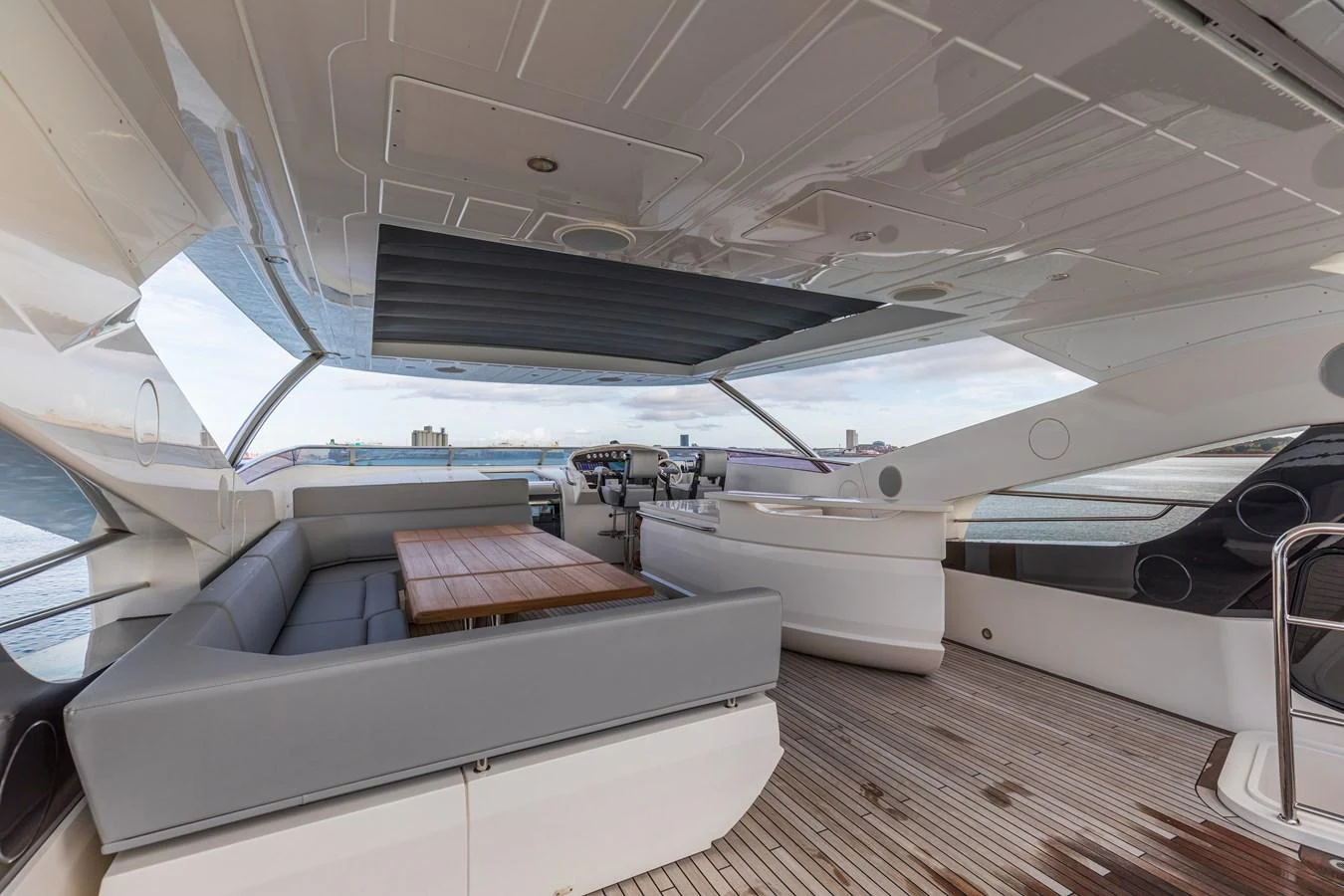 The flybridge features a spacious seating area with a wooden table and panoramic views. aboard CLOUDIA Yacht for Sale