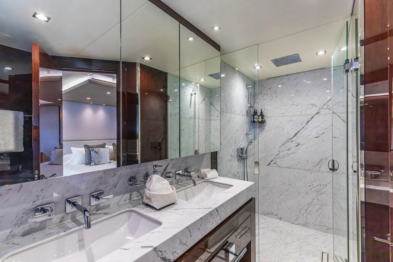 The yacht's bathroom features a luxurious marble design with dual sinks and a spacious glass-enclosed shower. aboard CLOUDIA Yacht for Sale