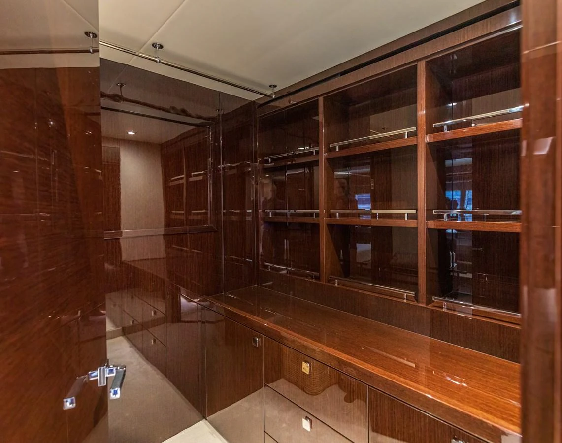 The image showcases a luxurious interior space with glossy wooden cabinetry and shelving. aboard CLOUDIA Yacht for Sale