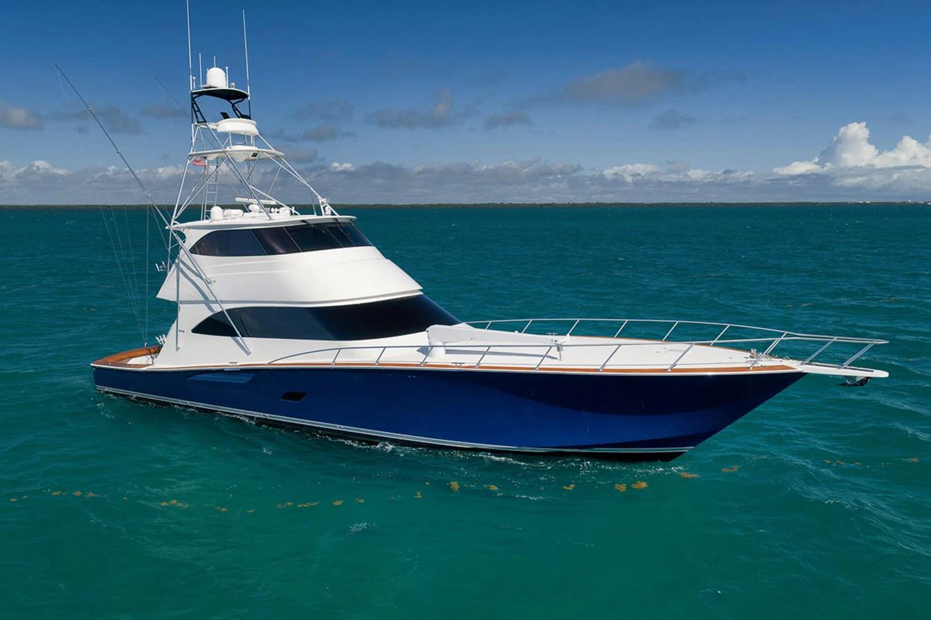 A sleek and modern yacht glides gracefully on the open sea under a clear blue sky. aboard REEL HAWK Yacht for Sale
