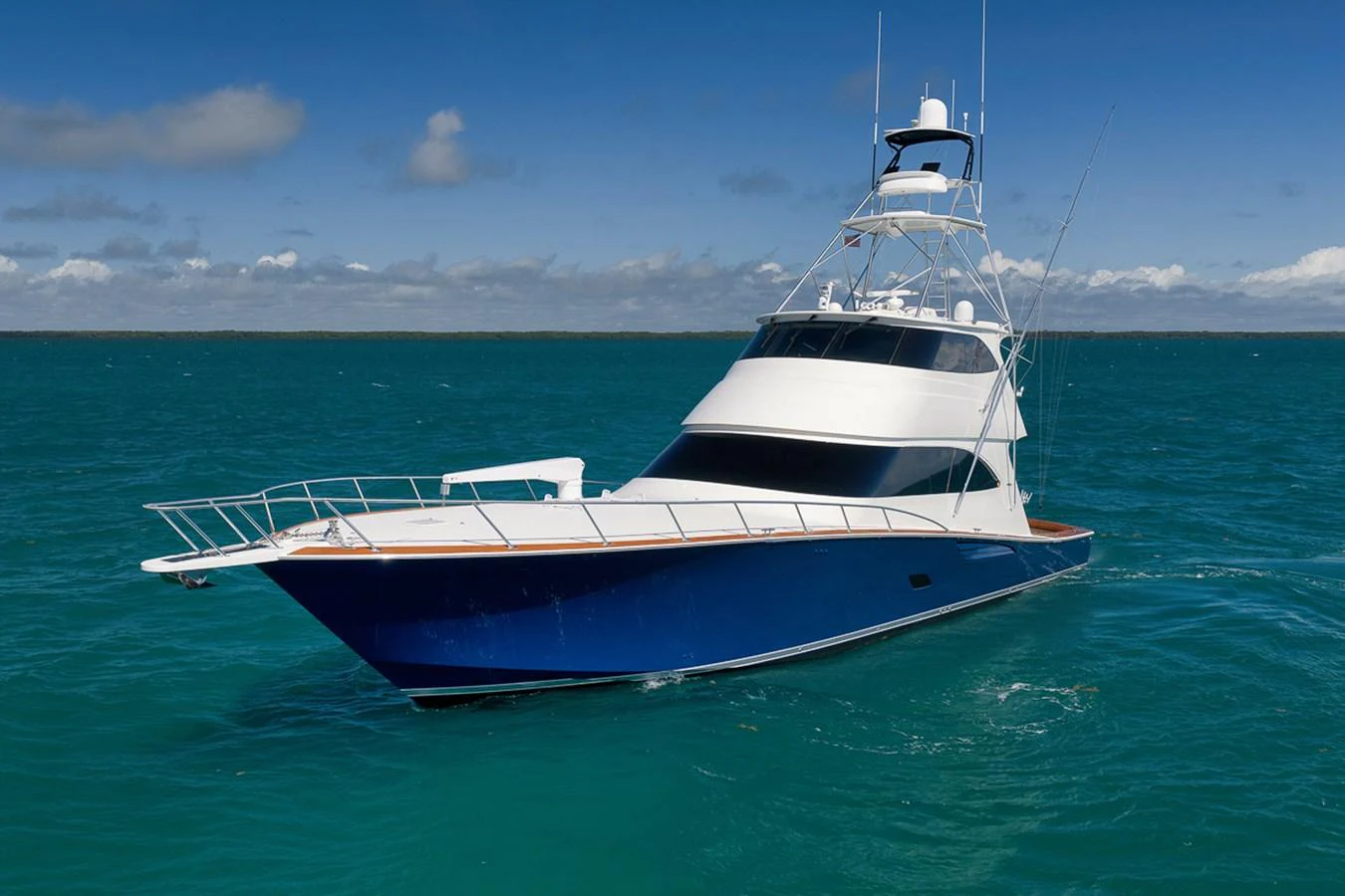 A sleek yacht glides through turquoise waters under a clear blue sky. aboard REEL HAWK Yacht for Sale