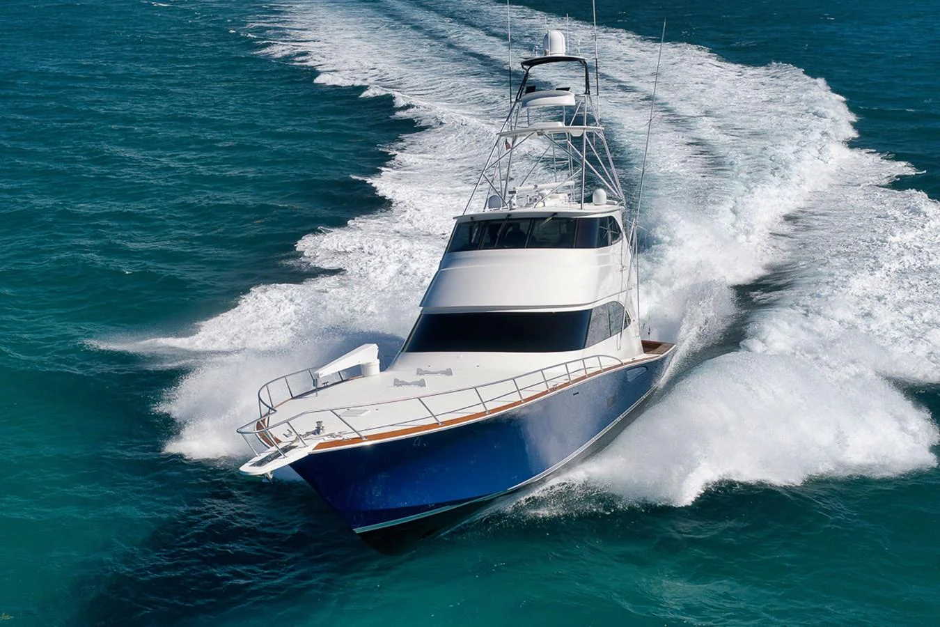 A sleek yacht cruises powerfully through the vibrant blue waters, leaving a dynamic wake behind. aboard REEL HAWK Yacht for Sale
