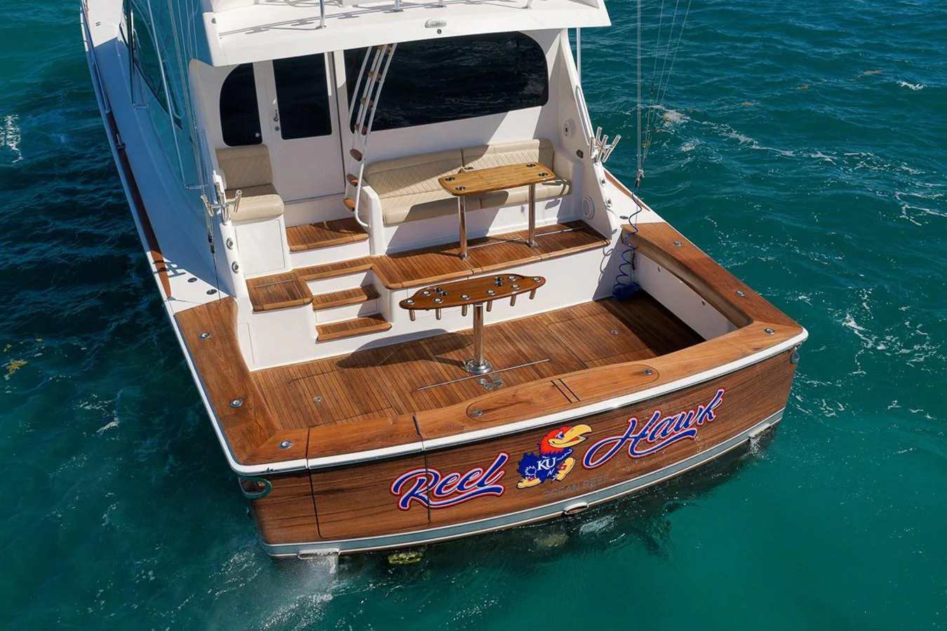 The yacht's aft deck features a spacious area with wooden flooring and comfortable seating, perfect for relaxation and fishing. aboard REEL HAWK Yacht for Sale