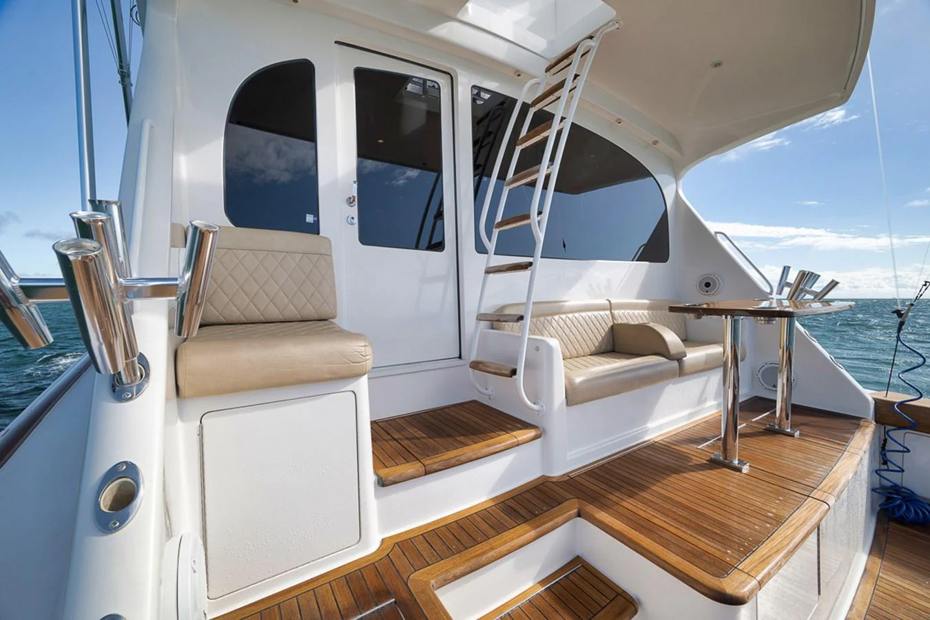 The aft deck features comfortable seating and a polished wooden floor, perfect for relaxing while enjoying the sea view. aboard REEL HAWK Yacht for Sale