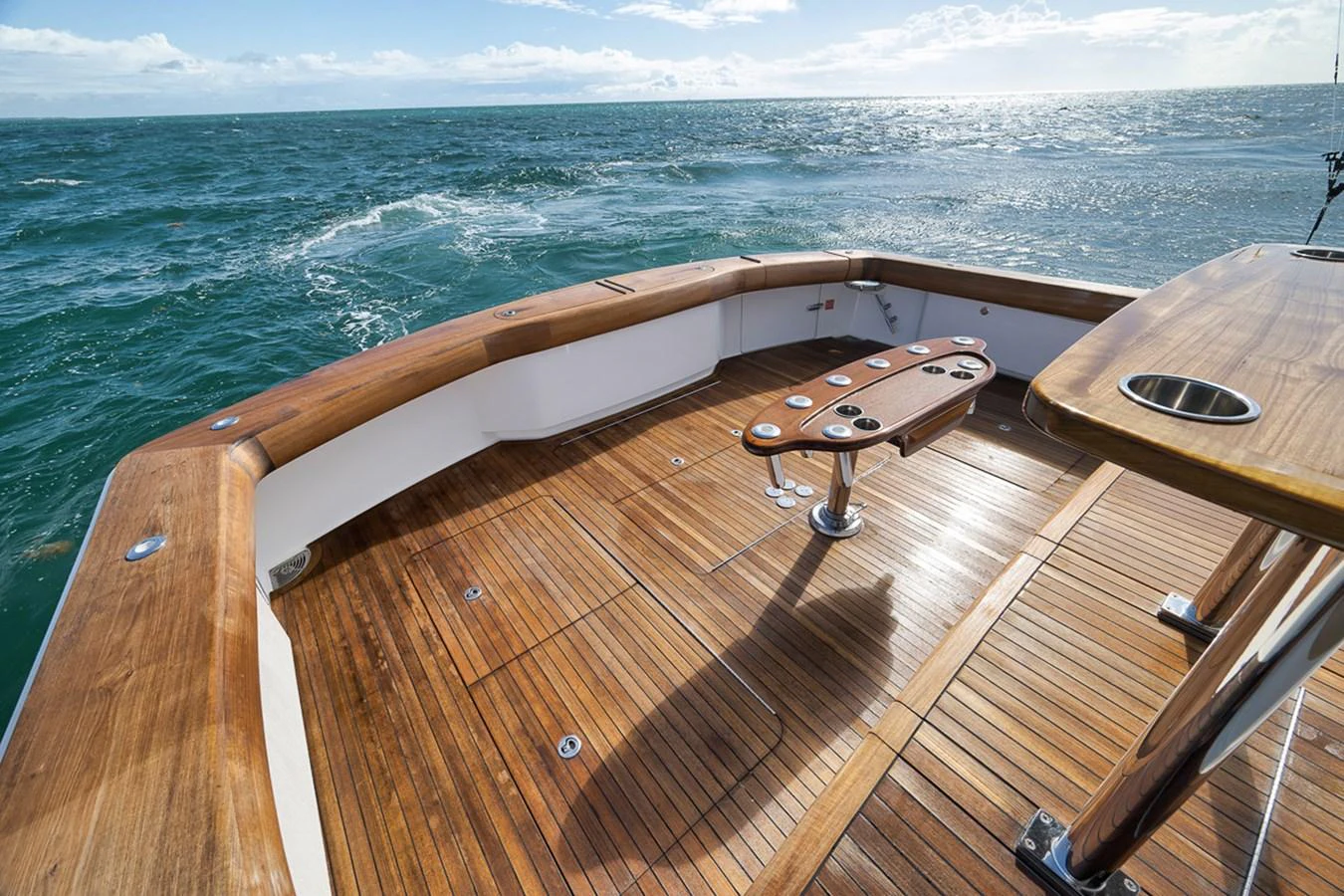 The aft deck features a spacious and elegant teak flooring with a central table, perfect for outdoor leisure. aboard REEL HAWK Yacht for Sale