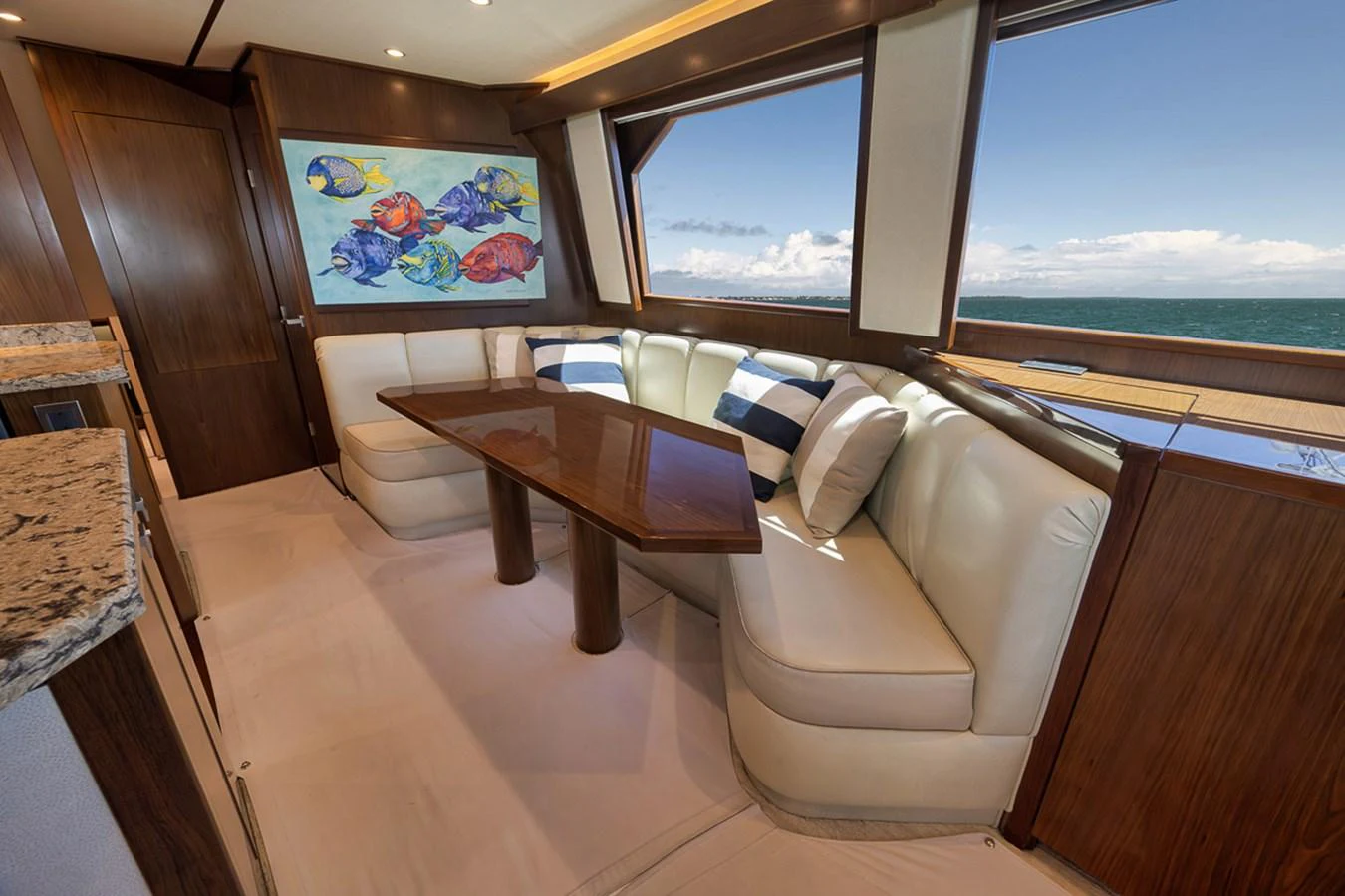 The salon features a comfortable seating area with a polished wooden table and large windows offering stunning ocean views. aboard REEL HAWK Yacht for Sale