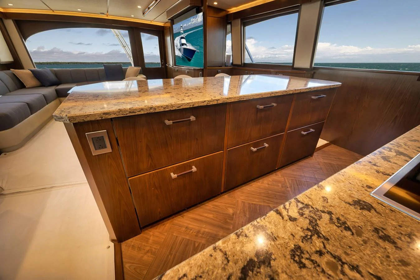 The galley features elegant wooden cabinetry and a spacious countertop with a stunning ocean view through large windows. aboard REEL HAWK Yacht for Sale