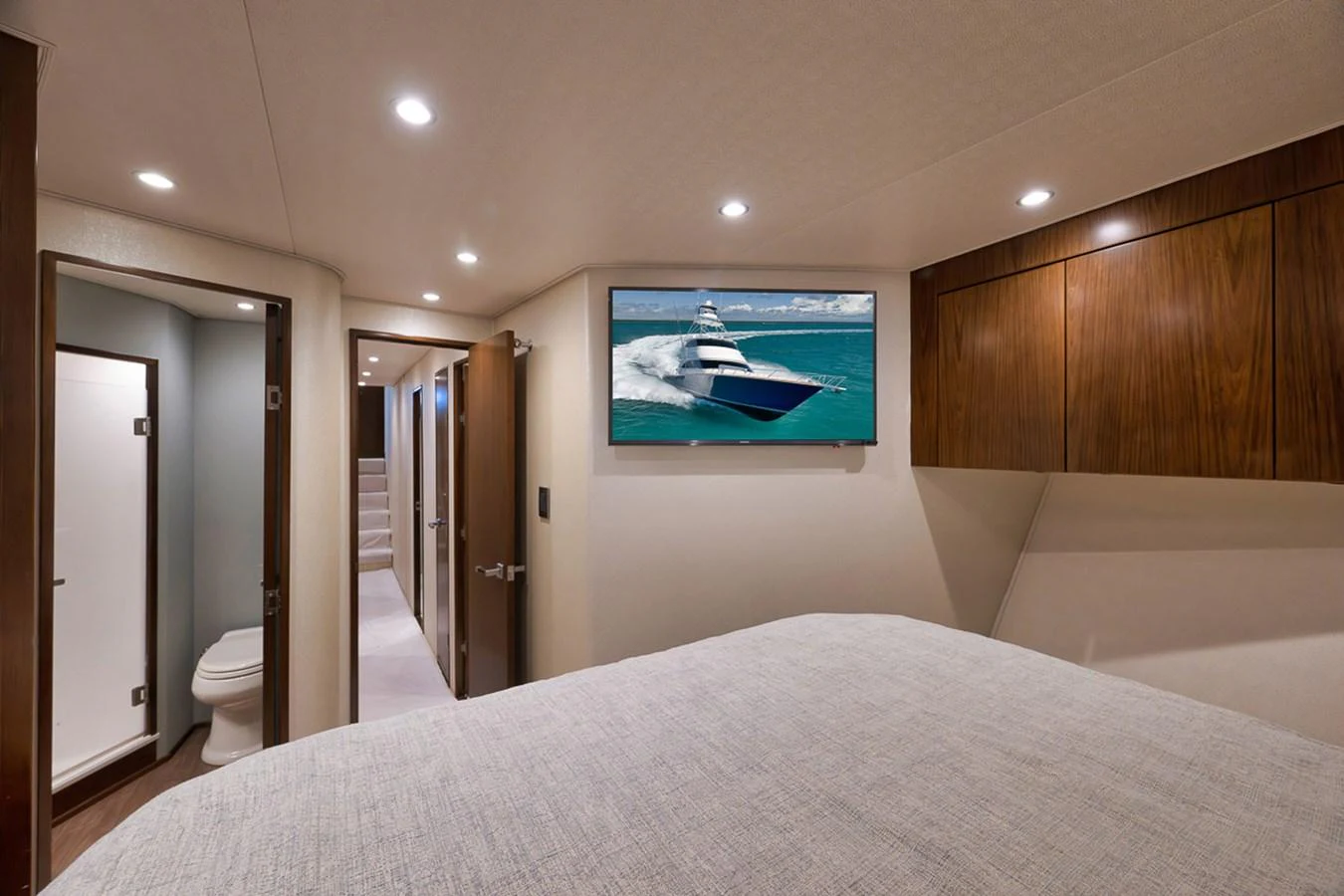 A cozy stateroom featuring a comfortable bed, wooden cabinetry, and a flat-screen TV displaying a yacht. aboard REEL HAWK Yacht for Sale