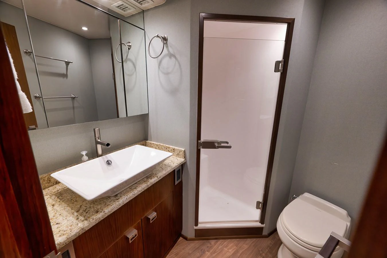 A modern yacht bathroom featuring a sleek sink, granite countertop, and a glass-enclosed shower. aboard REEL HAWK Yacht for Sale