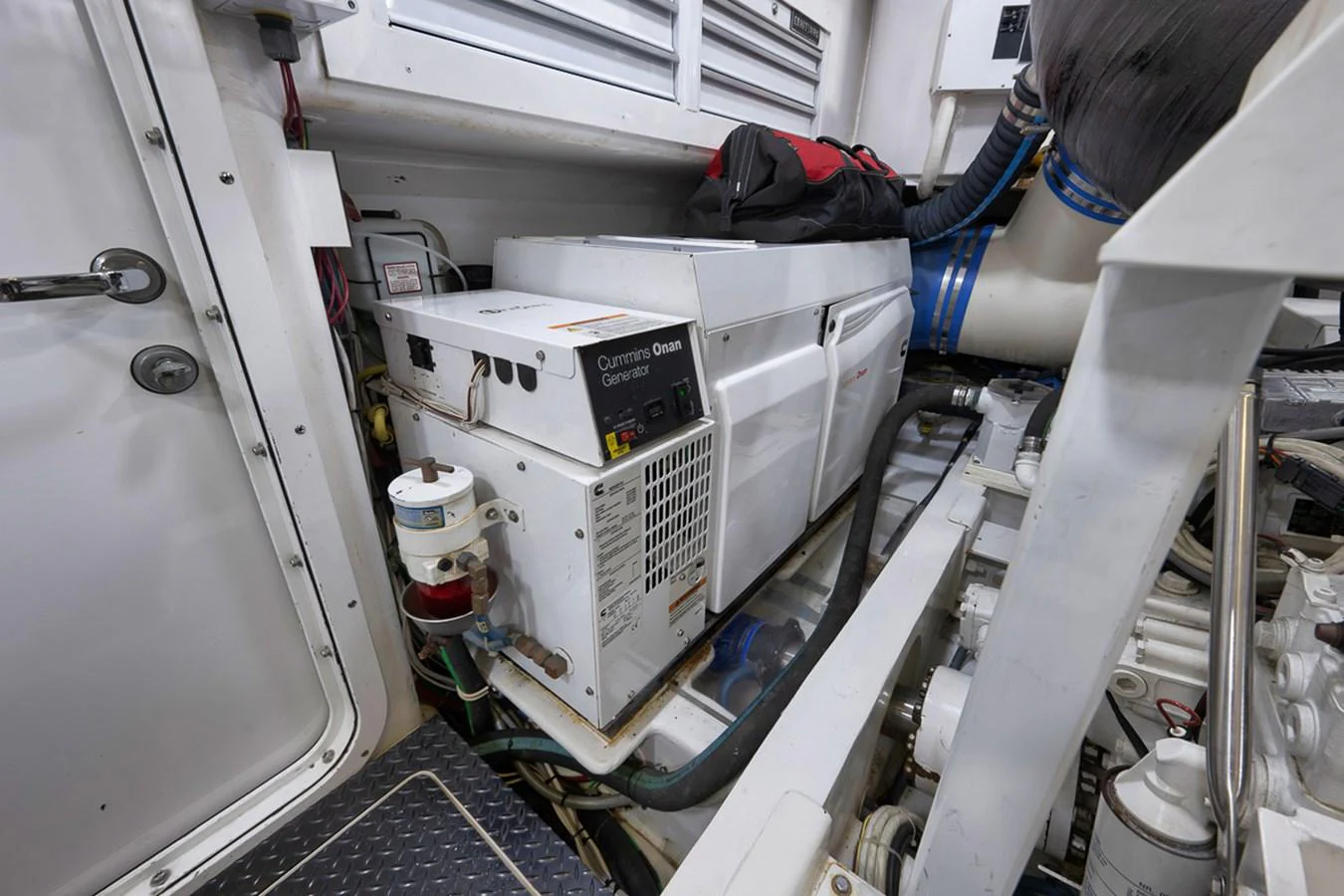 The image showcases the yacht's engine room with a Cummins Onan generator. aboard REEL HAWK Yacht for Sale