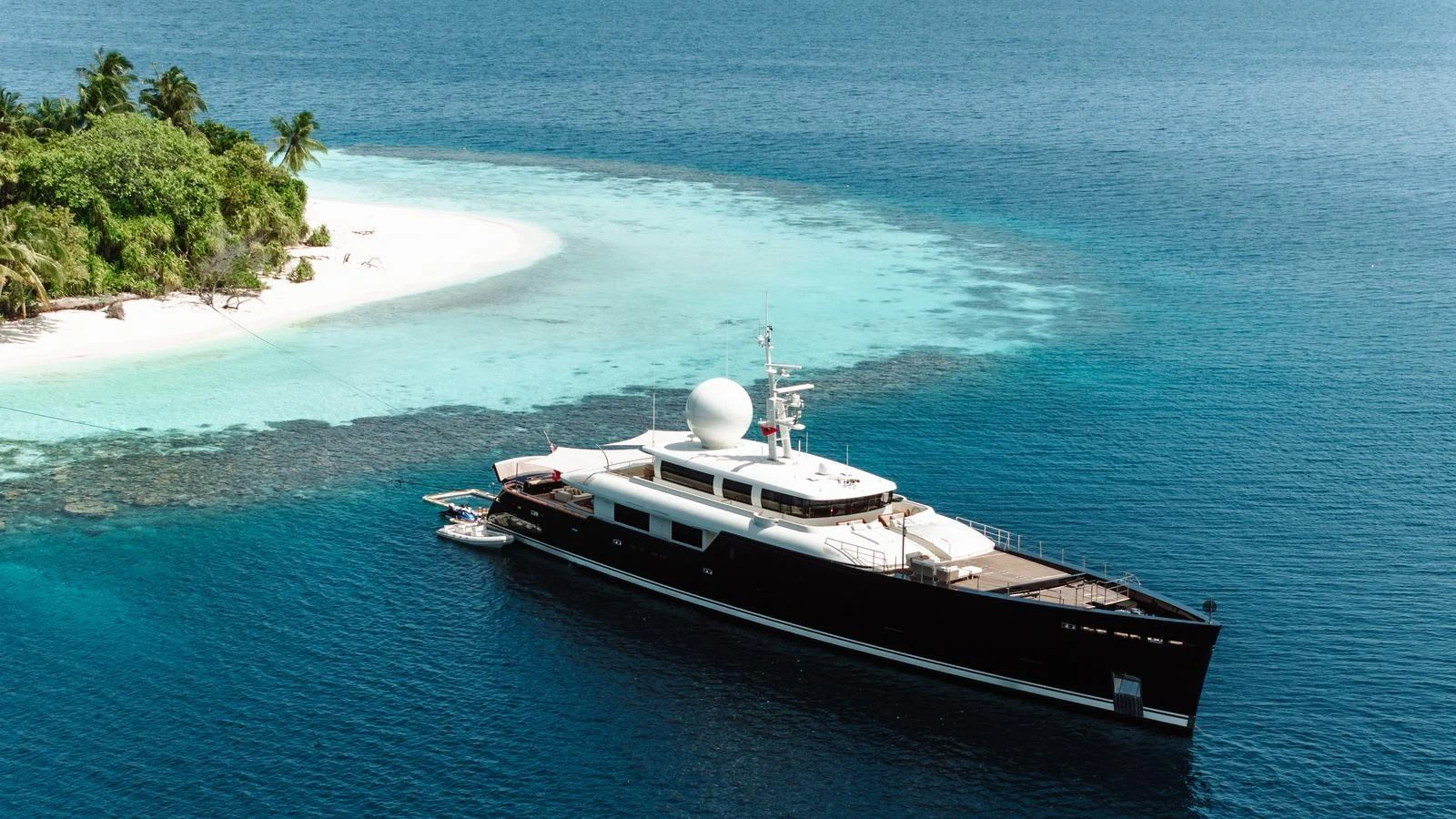 A sleek yacht cruises near a tropical island with crystal-clear waters and lush greenery. aboard GALILEO Yacht for Sale