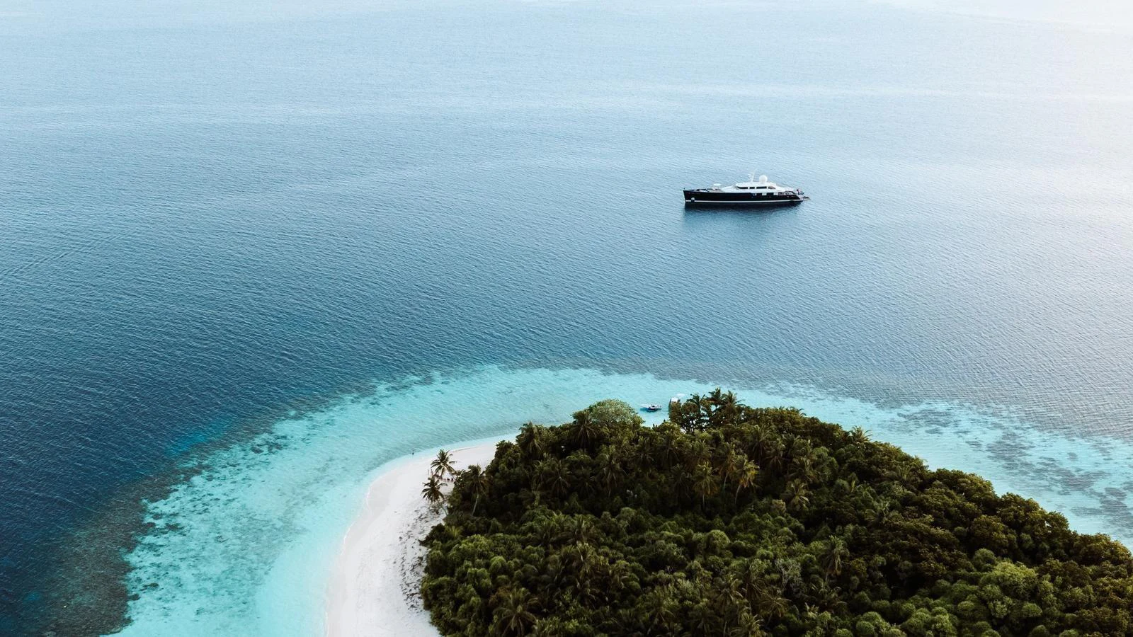 A luxurious yacht is anchored near a pristine tropical island with clear blue waters. aboard GALILEO Yacht for Sale