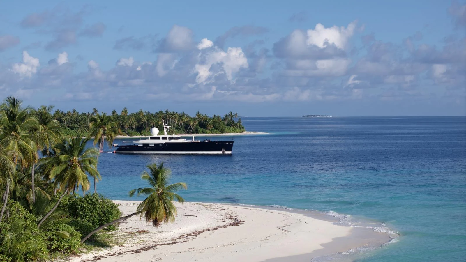 A sleek yacht is anchored near a tropical island with pristine beaches and clear blue waters. aboard GALILEO Yacht for Sale