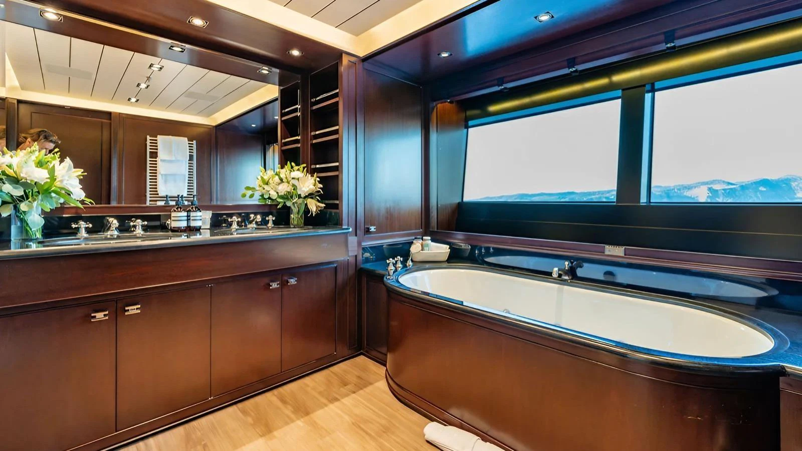The yacht's bathroom features elegant wood finishes, a large bathtub, and expansive windows with a scenic view. aboard GALILEO Yacht for Sale
