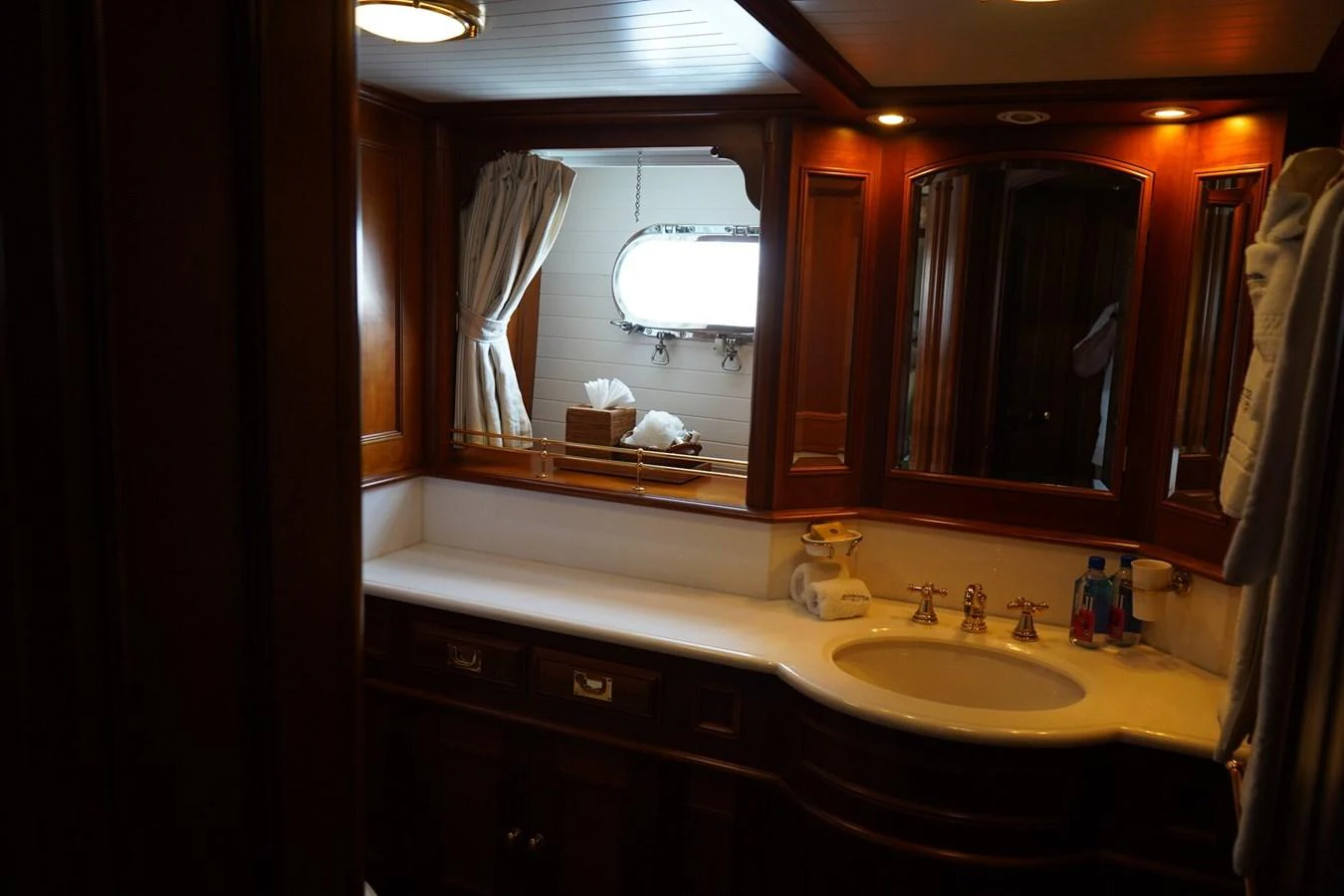 The yacht's bathroom features elegant wooden cabinetry and a well-lit vanity area. aboard KNICKERBOCKER Yacht for Sale