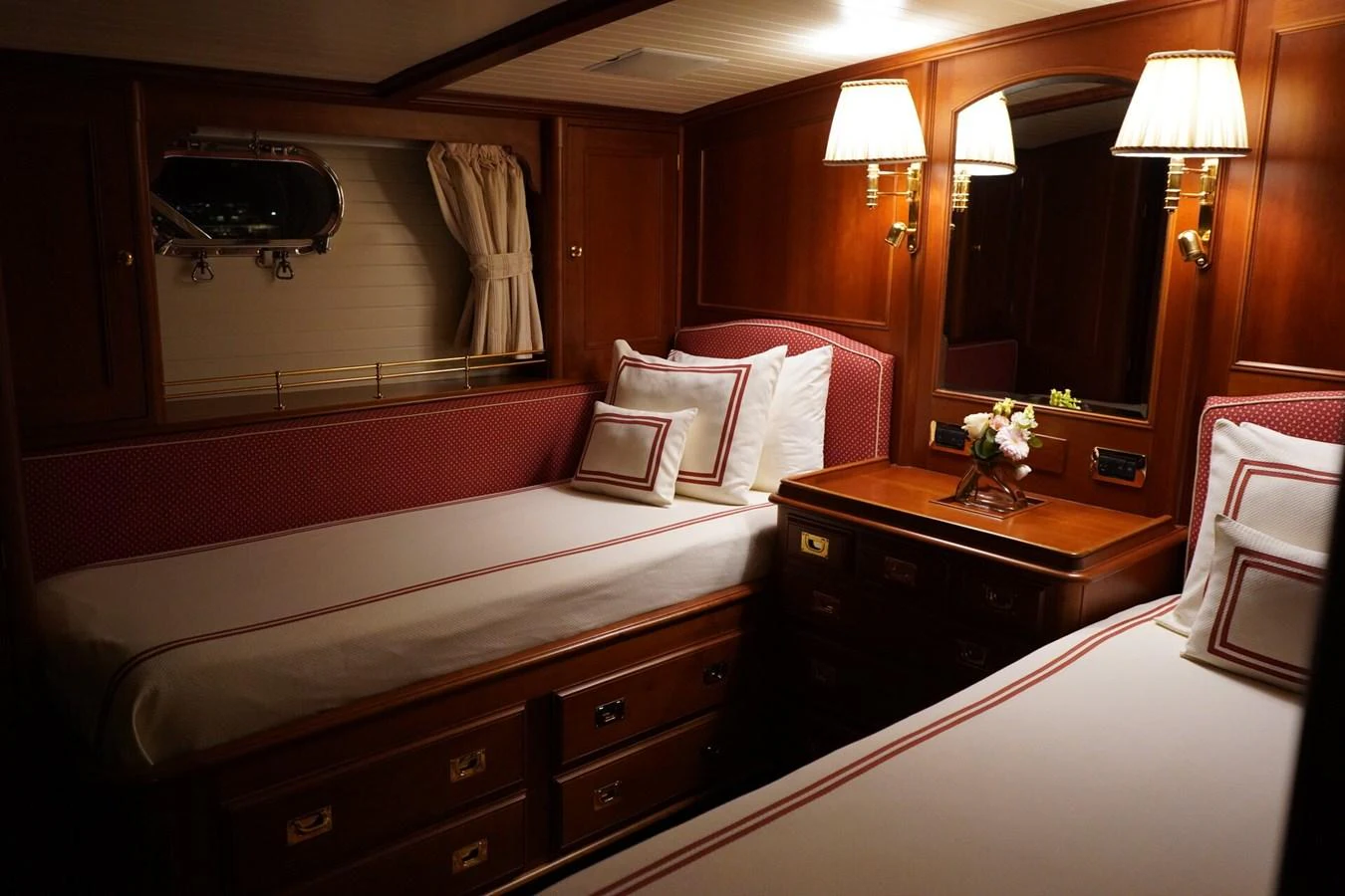 The guest stateroom features twin beds with elegant wooden furnishings and ambient lighting. aboard KNICKERBOCKER Yacht for Sale