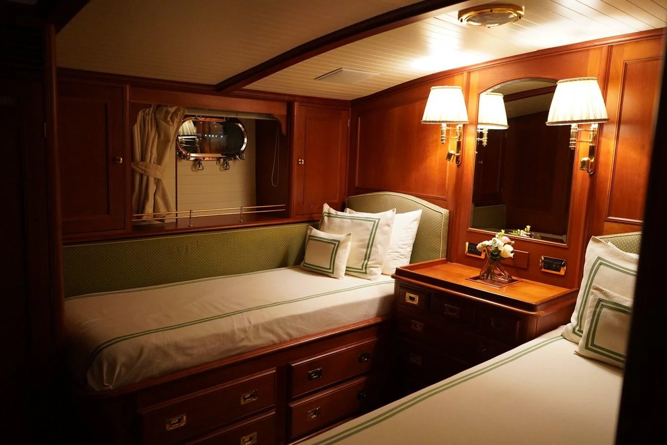 A cozy stateroom with twin beds, warm wood paneling, and elegant lighting. aboard KNICKERBOCKER Yacht for Sale