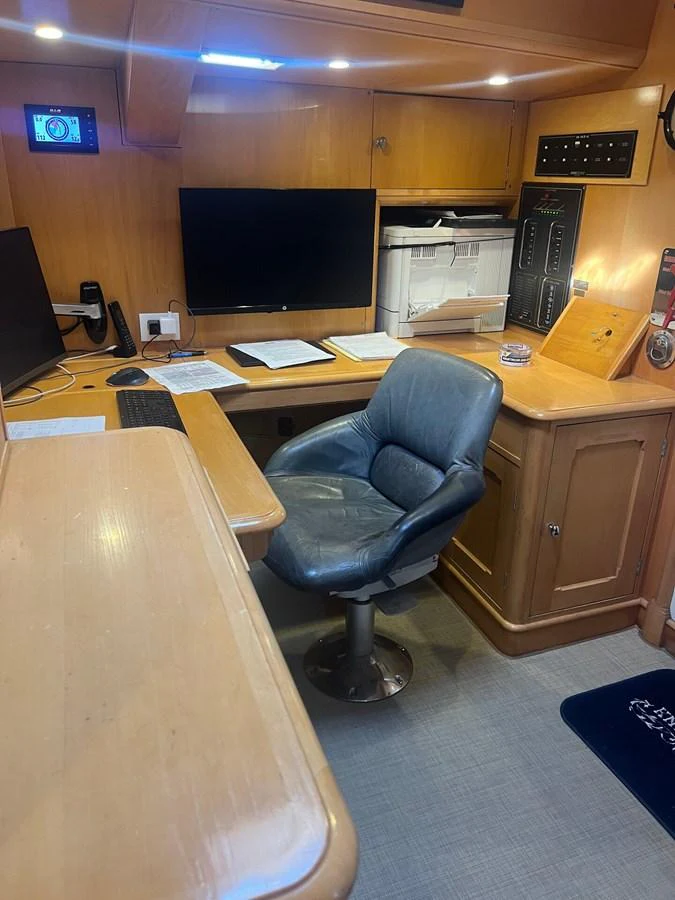 A cozy yacht office space with a comfortable chair and ample desk area for work. aboard KNICKERBOCKER Yacht for Sale