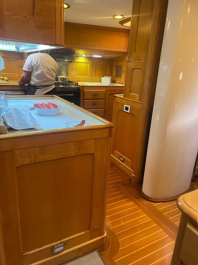 The yacht's galley features warm wooden cabinetry and modern appliances, creating a cozy and functional cooking space. aboard KNICKERBOCKER Yacht for Sale