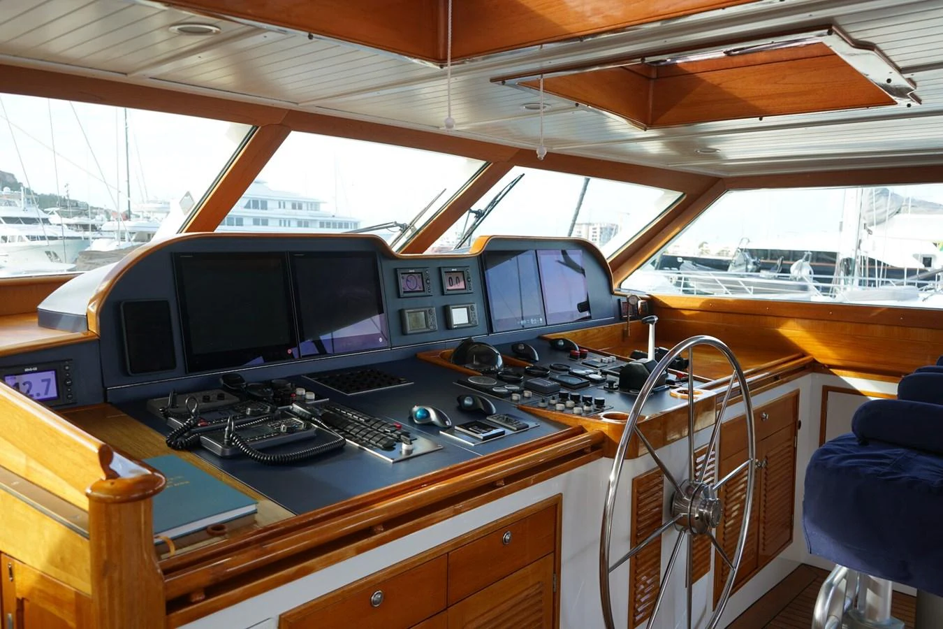 The helm station features advanced navigation equipment and a classic wooden steering wheel, offering a blend of modern technology and traditional craftsmanship. aboard KNICKERBOCKER Yacht for Sale