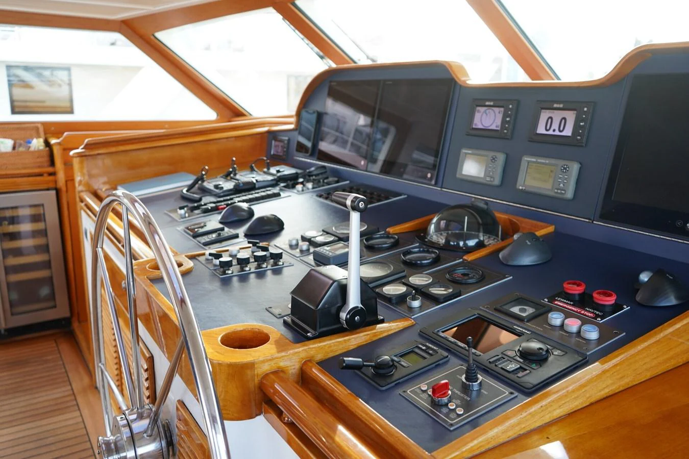The helm station features a sophisticated array of navigation and control instruments, complemented by a polished wooden steering wheel. aboard KNICKERBOCKER Yacht for Sale