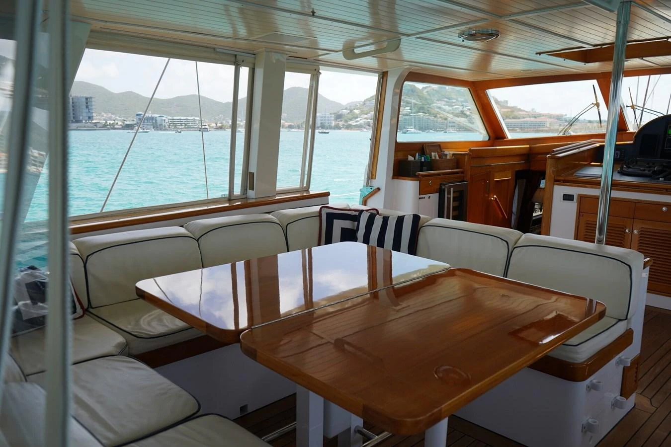 The salon features a spacious seating area with a polished wooden table and panoramic windows offering stunning views. aboard KNICKERBOCKER Yacht for Sale