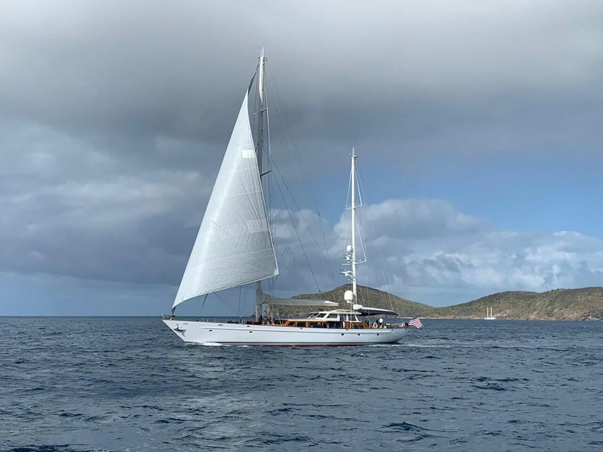 A sleek sailing yacht glides gracefully on the open sea under a cloudy sky. aboard KNICKERBOCKER Yacht for Sale