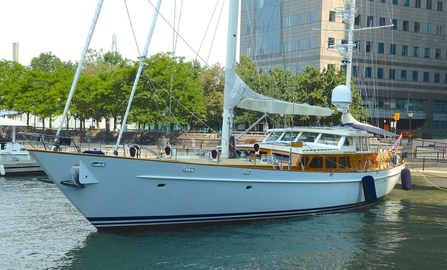 A sleek yacht is docked in a marina, showcasing its elegant design and spacious deck. aboard KNICKERBOCKER Yacht for Sale