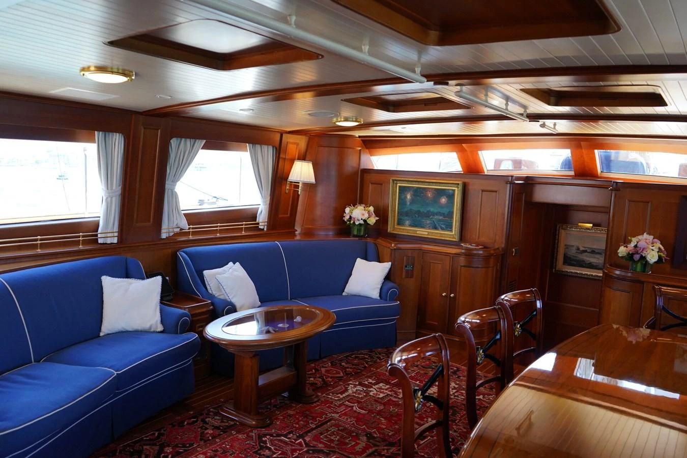 The yacht's salon features elegant wood paneling, plush blue seating, and tasteful decor. aboard KNICKERBOCKER Yacht for Sale