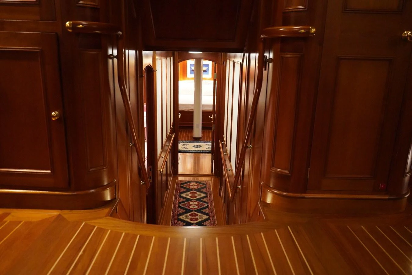 A luxurious wooden hallway leads to a cozy stateroom, showcasing elegant craftsmanship. aboard KNICKERBOCKER Yacht for Sale