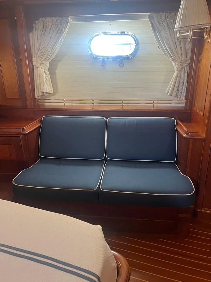 A cozy cabin with a blue cushioned bench and a porthole window, creating a warm and inviting atmosphere. aboard KNICKERBOCKER Yacht for Sale