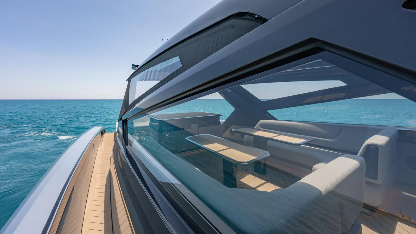 A sleek yacht with expansive windows reflecting the serene ocean view. aboard RESOLUTE Yacht for Sale