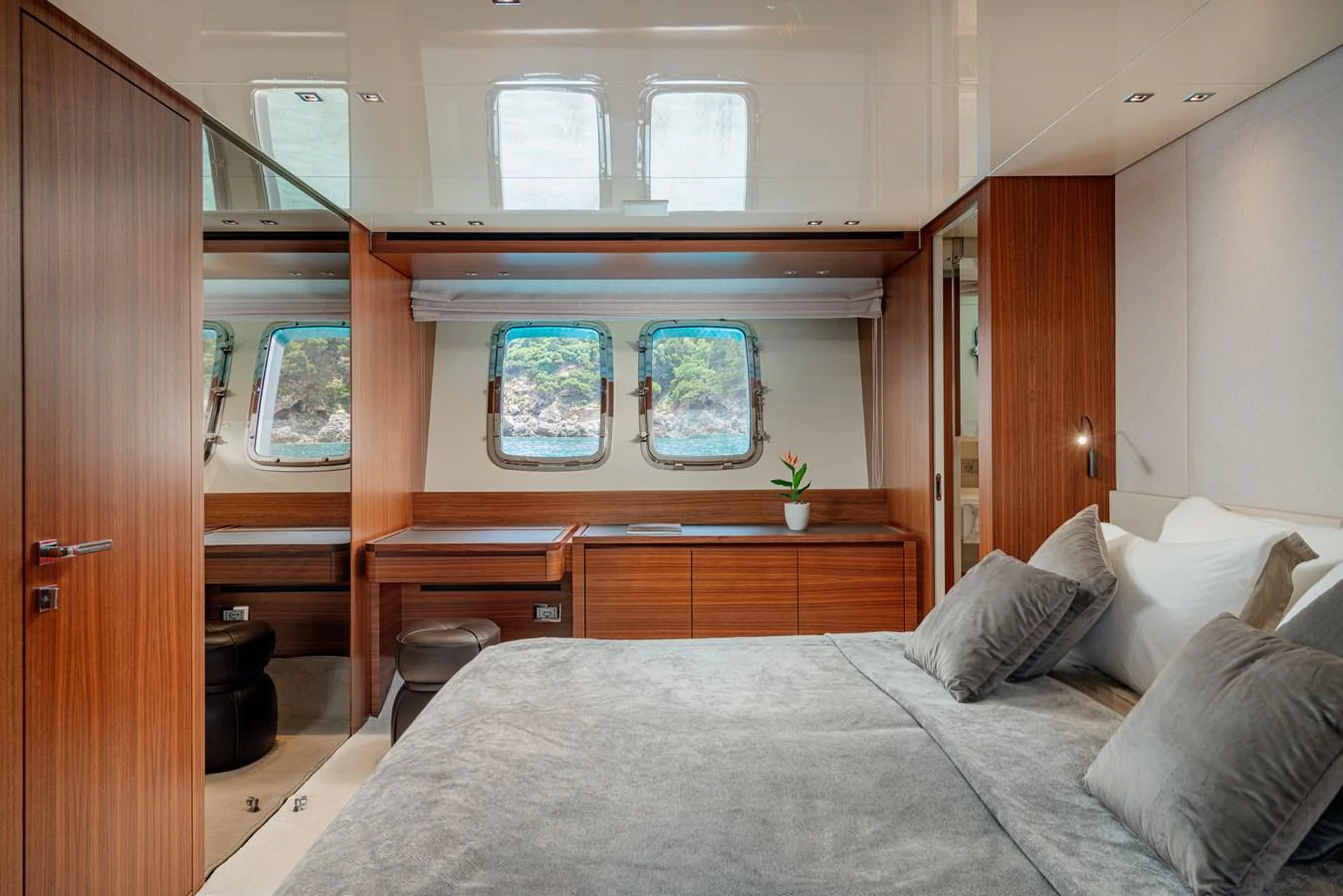 The stateroom features a luxurious bed with plush pillows and ample natural light from the windows. aboard M&M Yacht for Sale