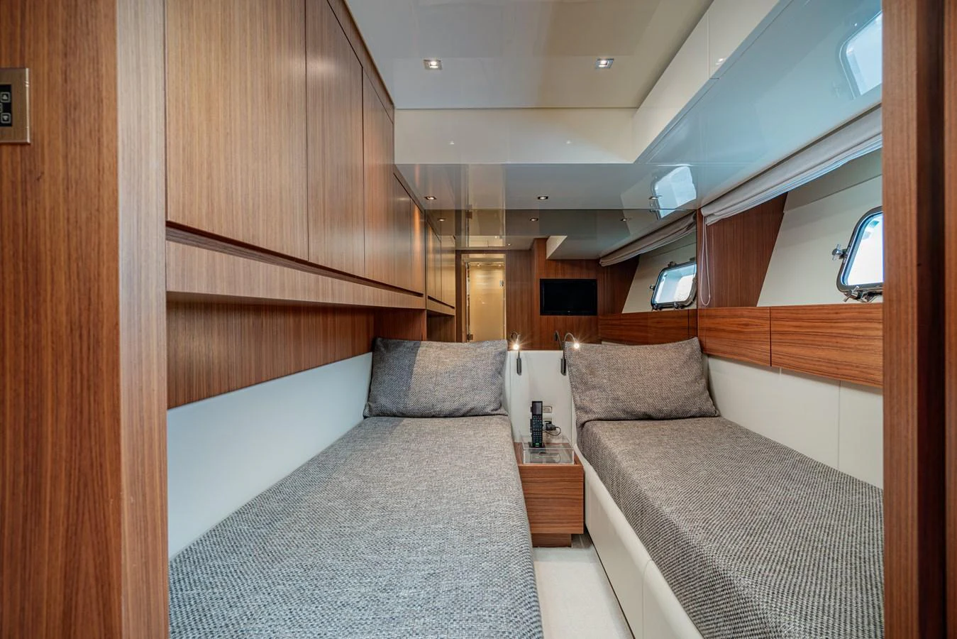 The twin stateroom features sleek wood paneling and comfortable bedding, creating a cozy and inviting atmosphere. aboard M&M Yacht for Sale