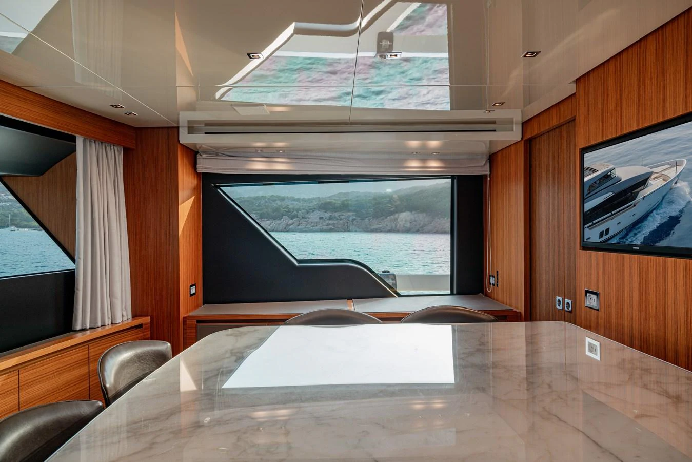 The yacht's interior features a stylish dining area with large windows offering scenic views. aboard M&M Yacht for Sale