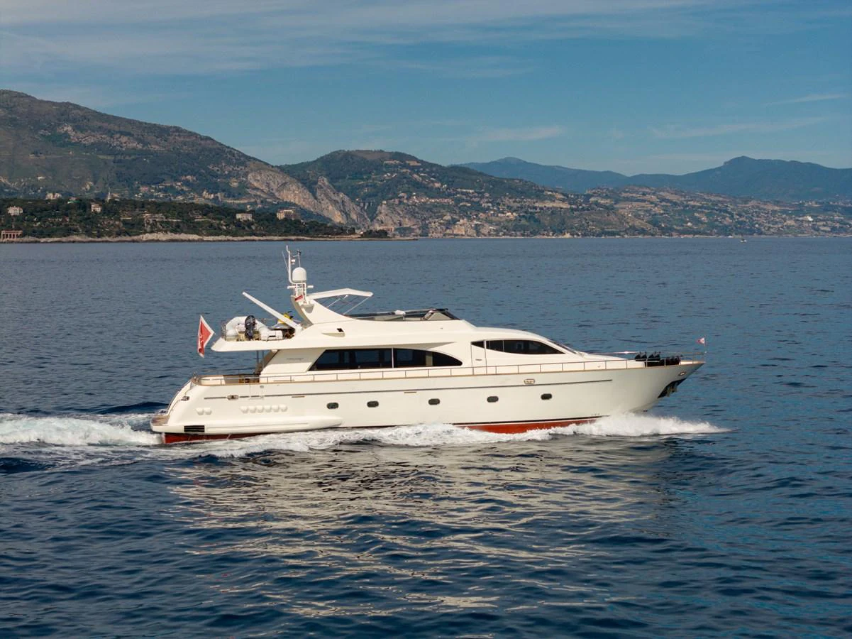 A sleek yacht cruises along a serene coastline under a clear blue sky. aboard LADY MAUREEN Yacht for Sale