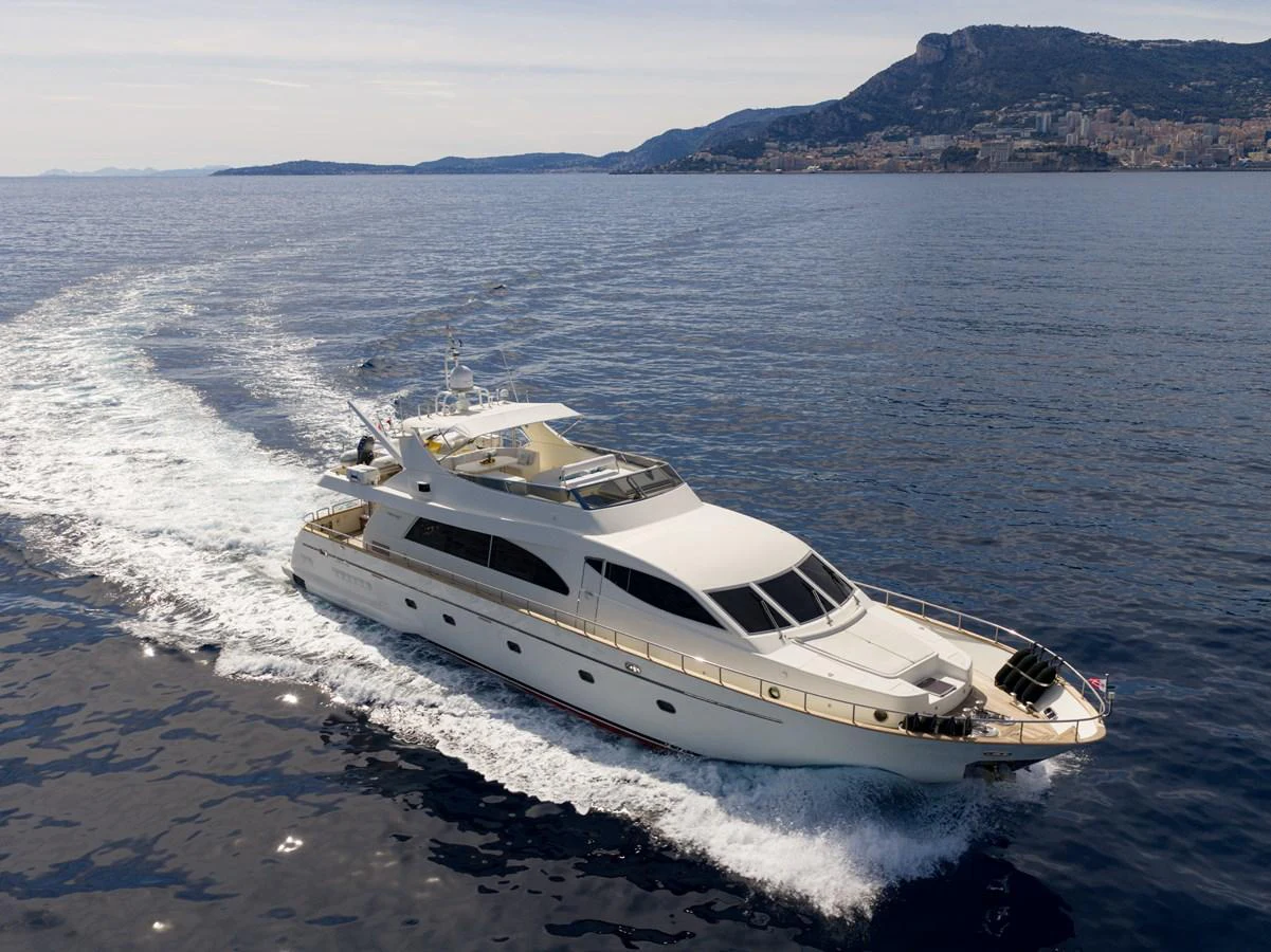 A luxurious yacht cruises through calm waters with a scenic coastal backdrop. aboard LADY MAUREEN Yacht for Sale