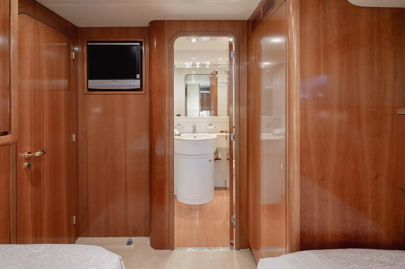 The cabin features warm wood paneling and a view into the ensuite bathroom. aboard LADY MAUREEN Yacht for Sale