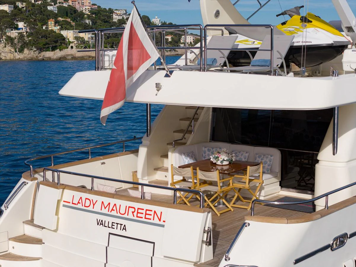 The aft deck of this yacht features a cozy seating area with a dining table, perfect for alfresco meals. aboard LADY MAUREEN Yacht for Sale