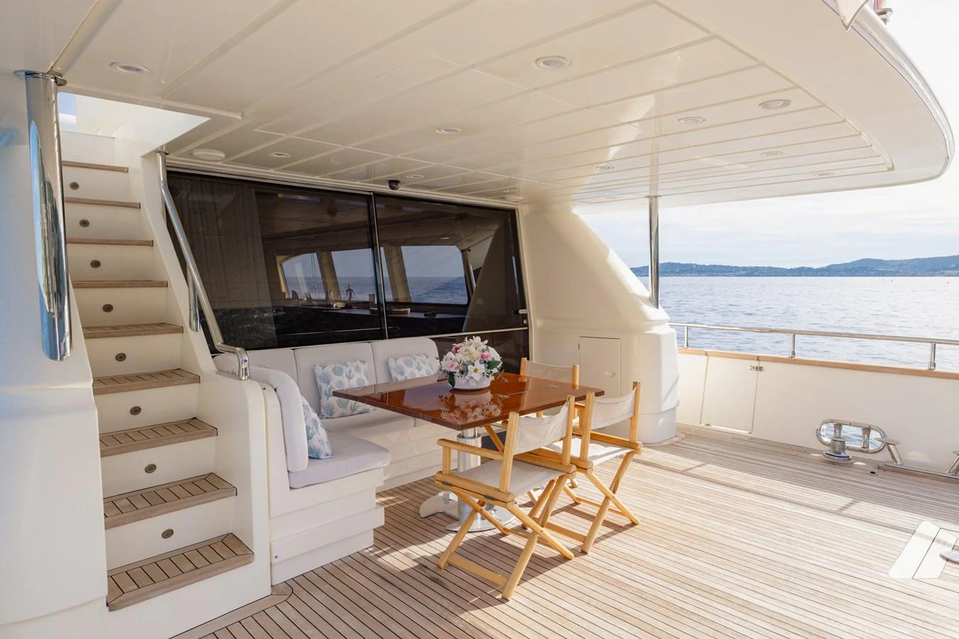 The aft deck features a cozy seating area with a wooden table and chairs, perfect for enjoying the ocean view. aboard LADY MAUREEN Yacht for Sale
