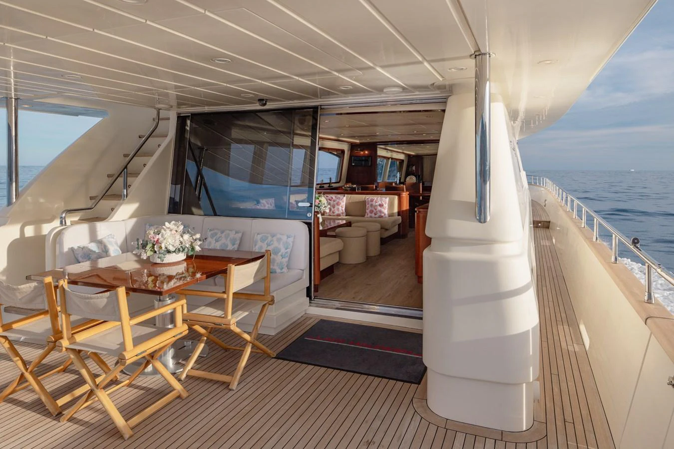 The aft deck features a cozy dining area with a view into the luxurious interior salon. aboard LADY MAUREEN Yacht for Sale