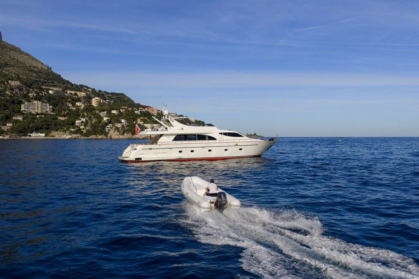 A sleek yacht cruises along the coastline, accompanied by a small tender boat. aboard LADY MAUREEN Yacht for Sale