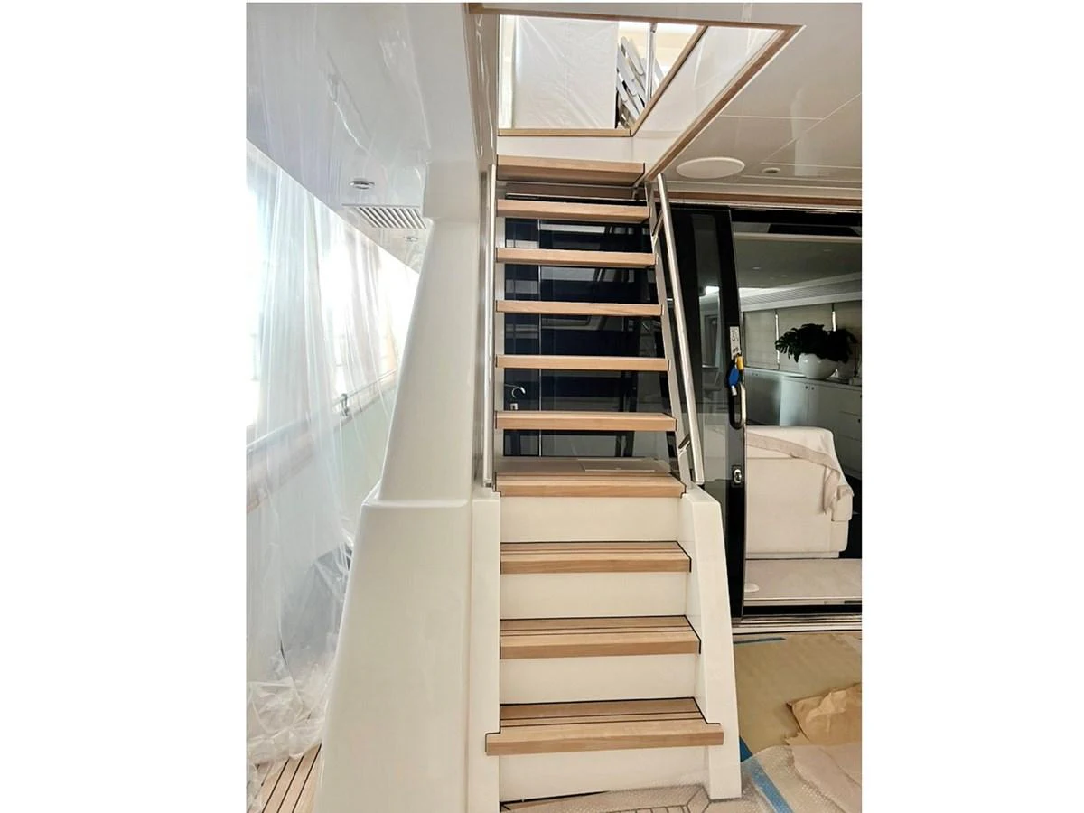 A sleek wooden staircase leads to the upper deck of the yacht, showcasing modern design and craftsmanship. aboard NICOSTASIA Yacht for Sale