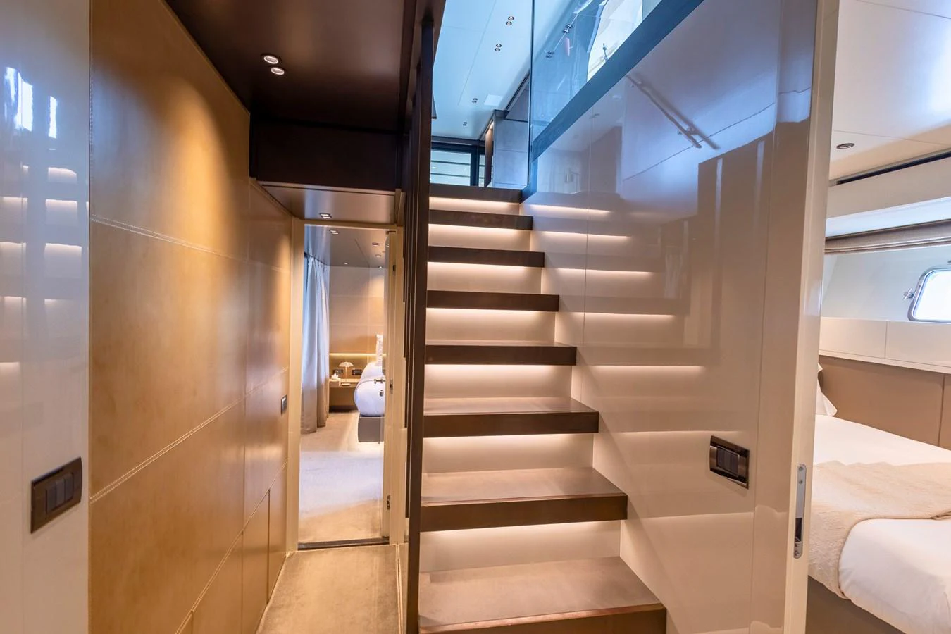 A modern yacht interior featuring a sleek, illuminated stairway leading to the upper deck. aboard ILIA Yacht for Sale